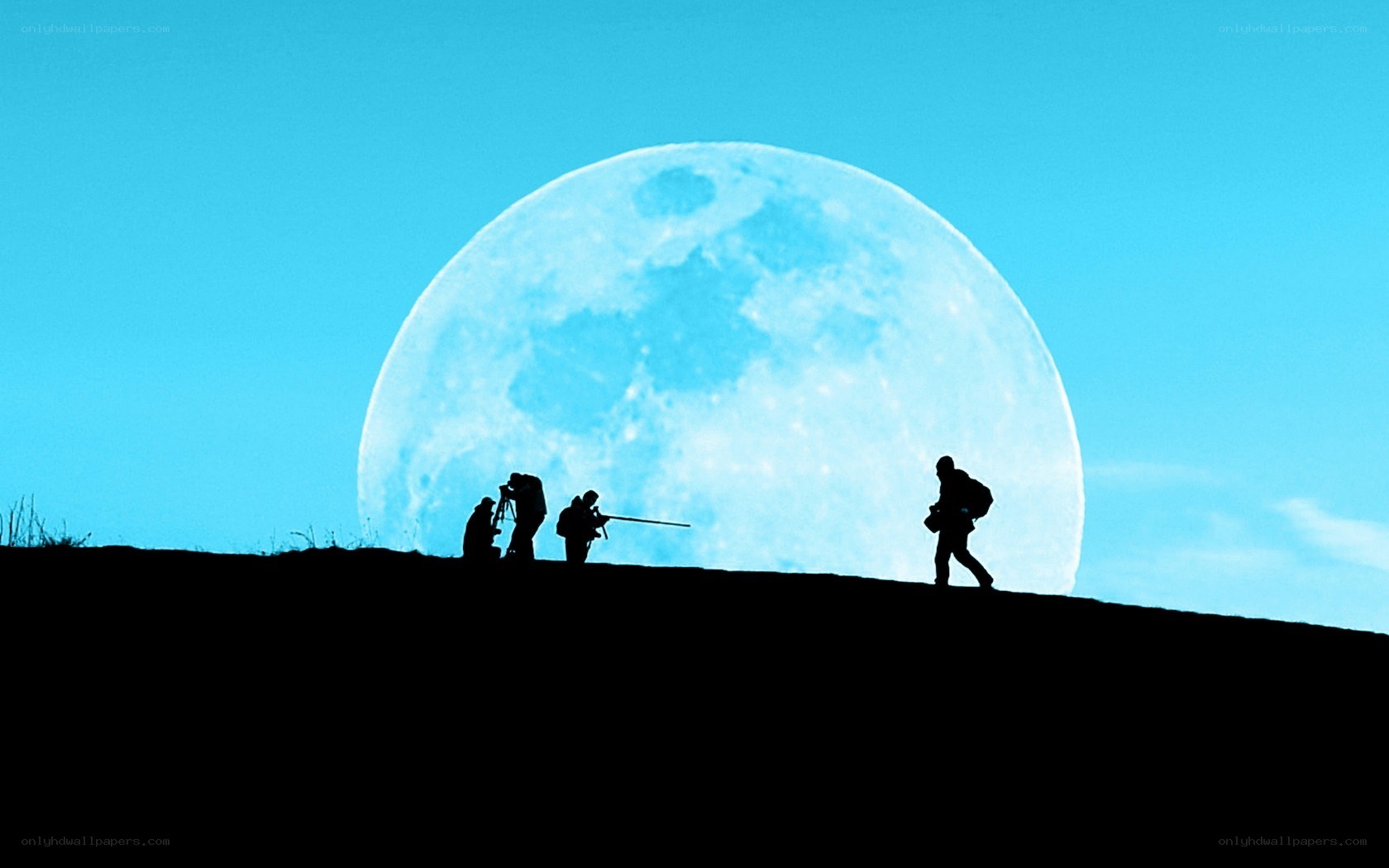 Photographers silhouetted against moon