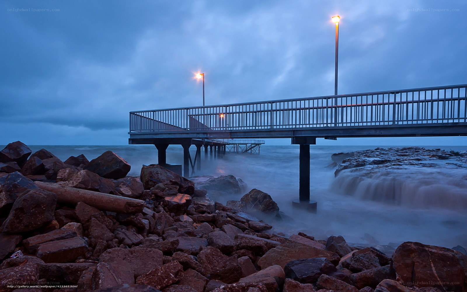 Pier at dusk with crashing waves