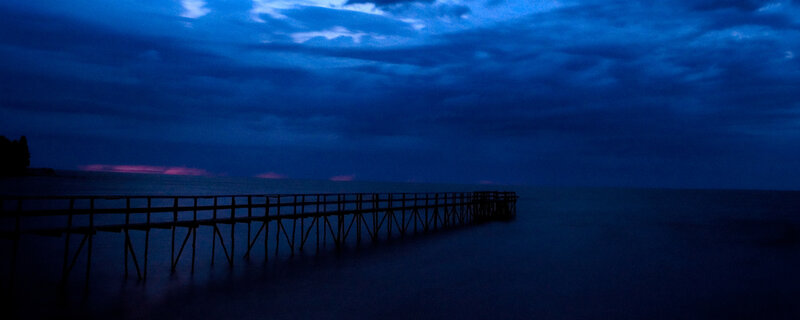 Pier at dusk with purple horizon
