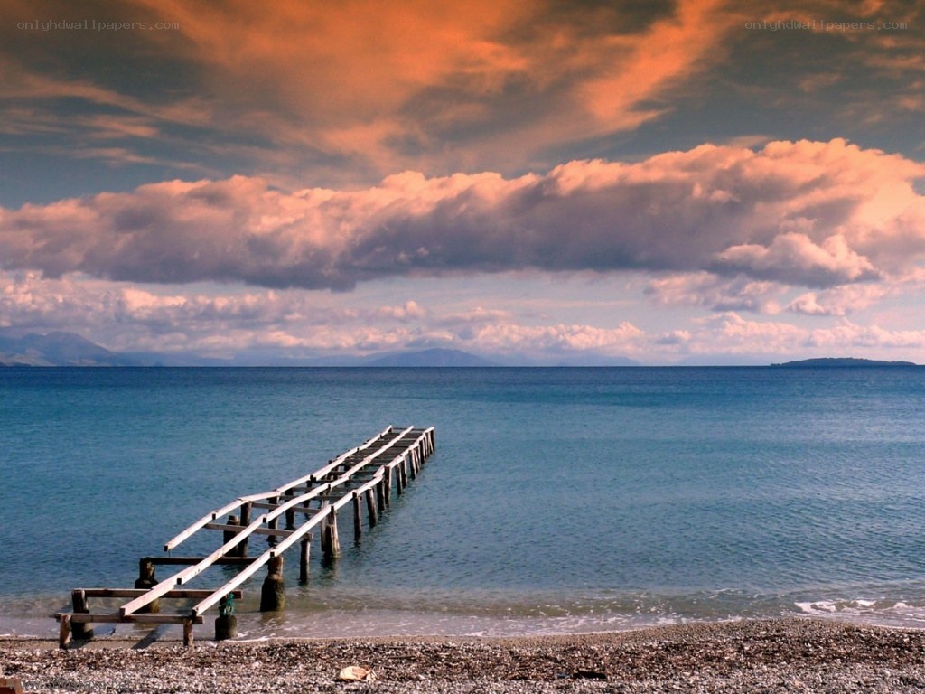 Pier at sunset on a pebble beach