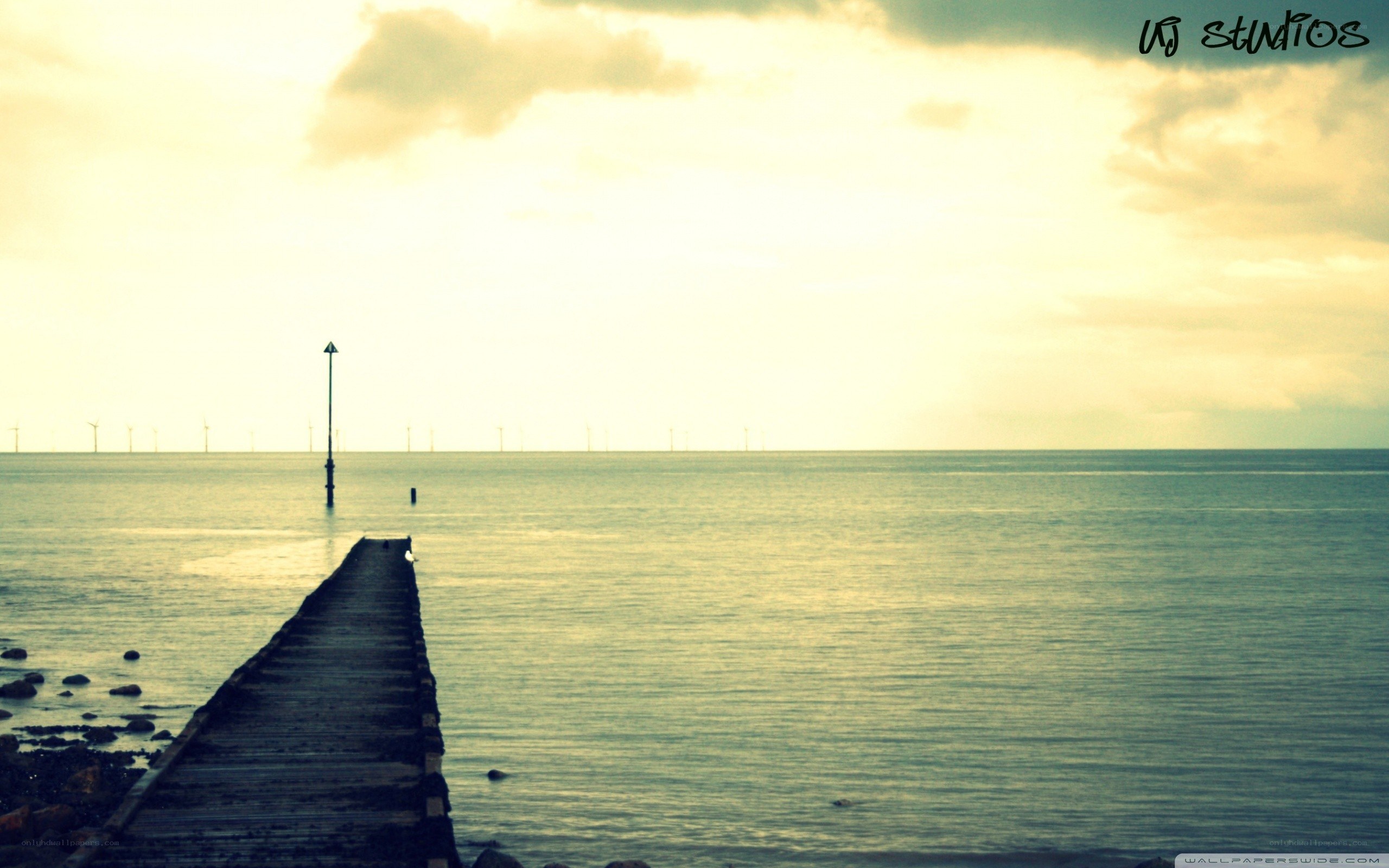 Pier at sunset with wind turbines