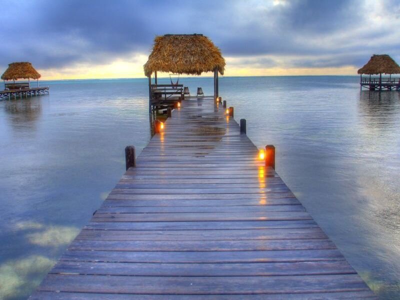 Pier with thatched huts at sunset