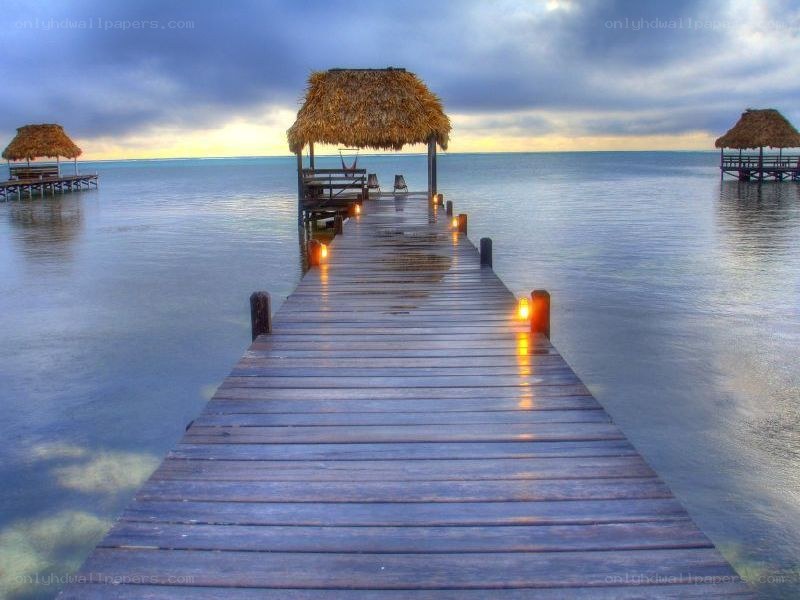 Pier with thatched huts at sunset