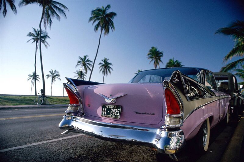 Pink classic car on a tropical road