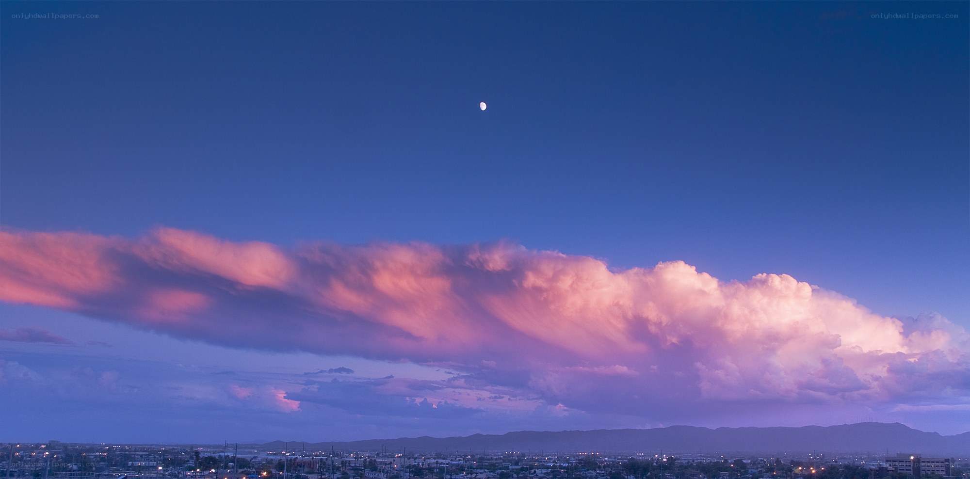 Pink cloud over city at dusk