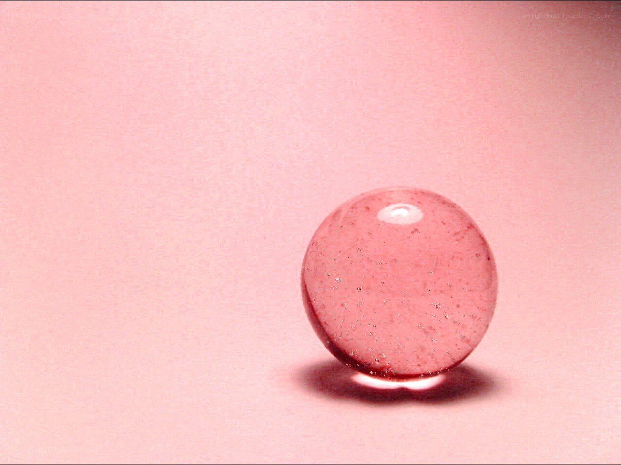 Pink glass marble on pink surface