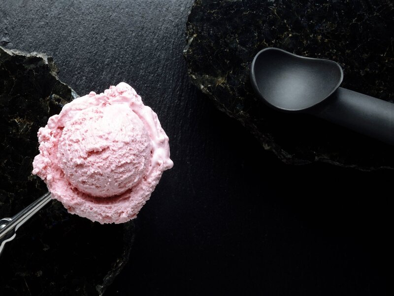 Pink ice cream scoop on dark stone