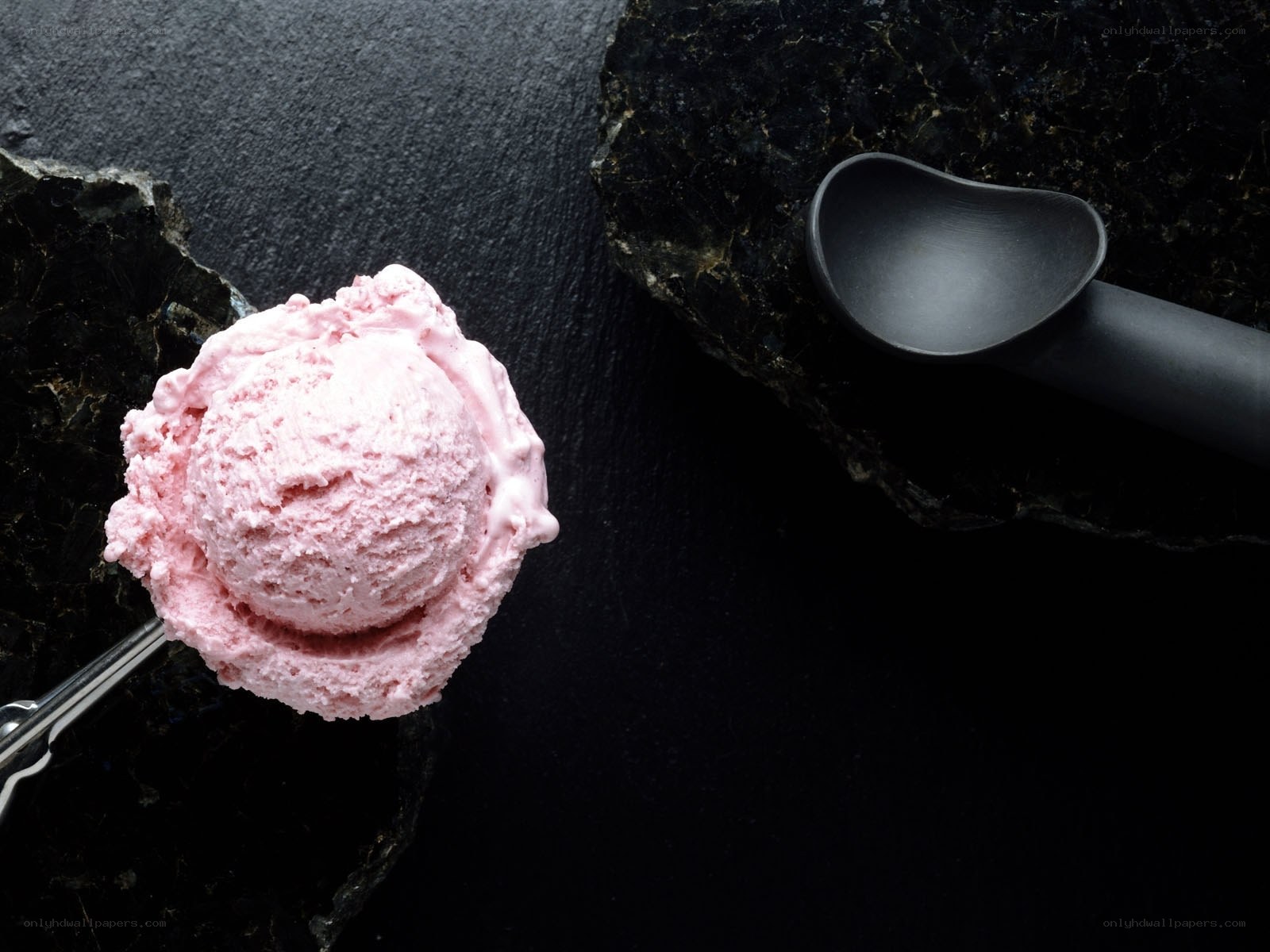 Pink ice cream scoop on dark stone