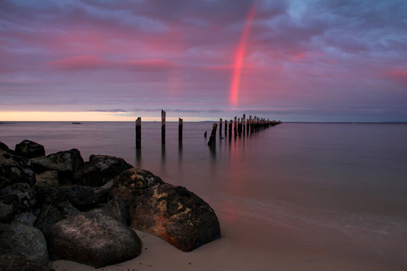 Pink rainbow over a pier