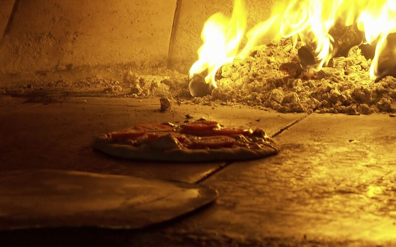 Pizza baking in a wood-fired oven