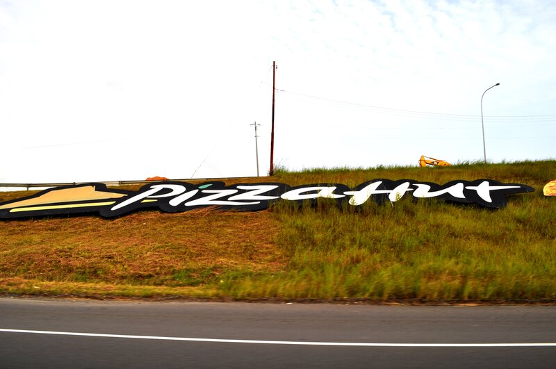 Pizza Hut sign on a roadside hill