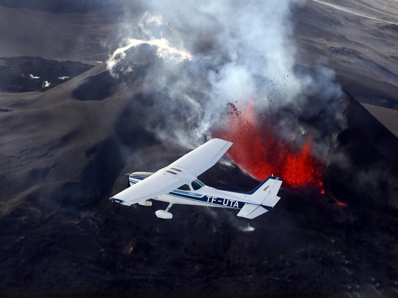 Plane flying over erupting volcano