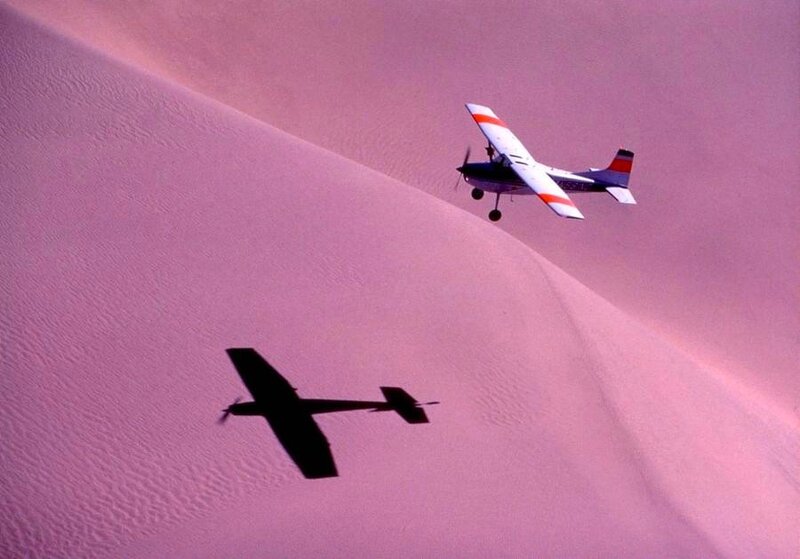 Plane flying over pink sand dunes