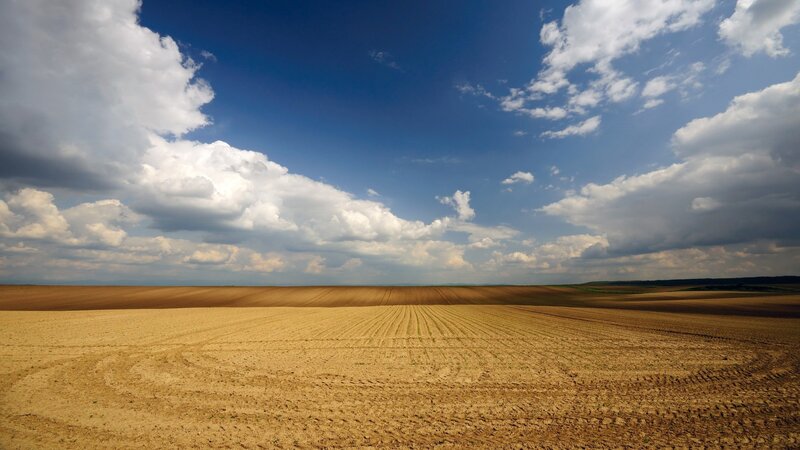 Plowed field under cloudy sky