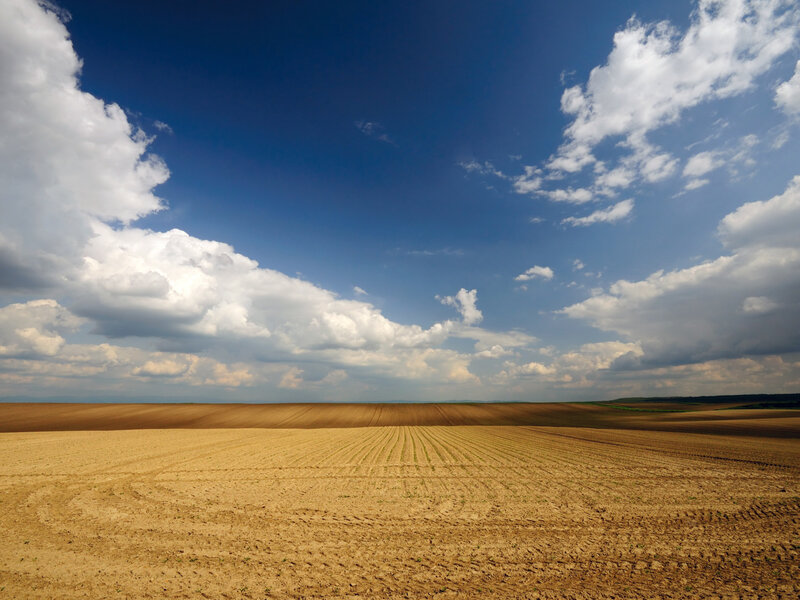 Plowed field under cloudy sky