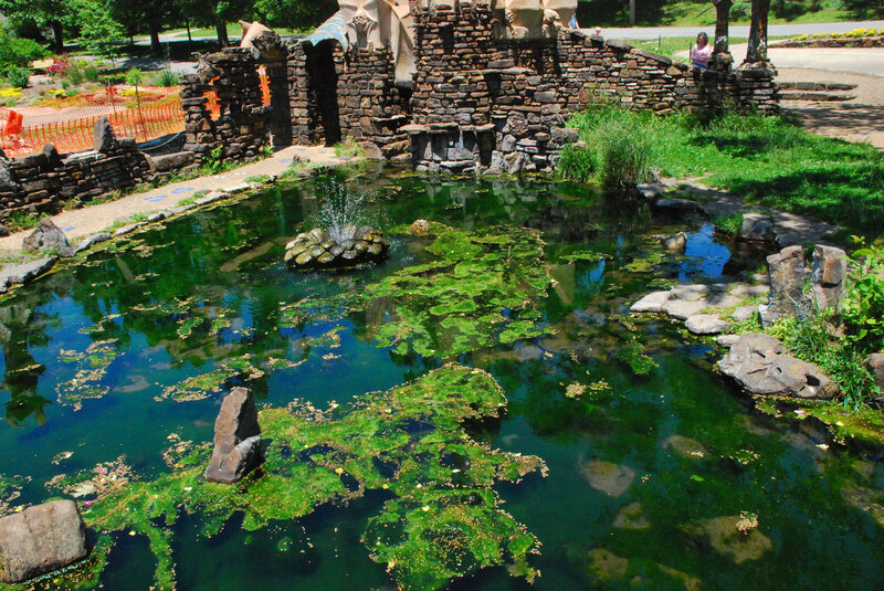 pond with fountain and stone ruins