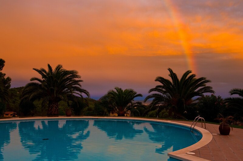 Pool with rainbow at sunset