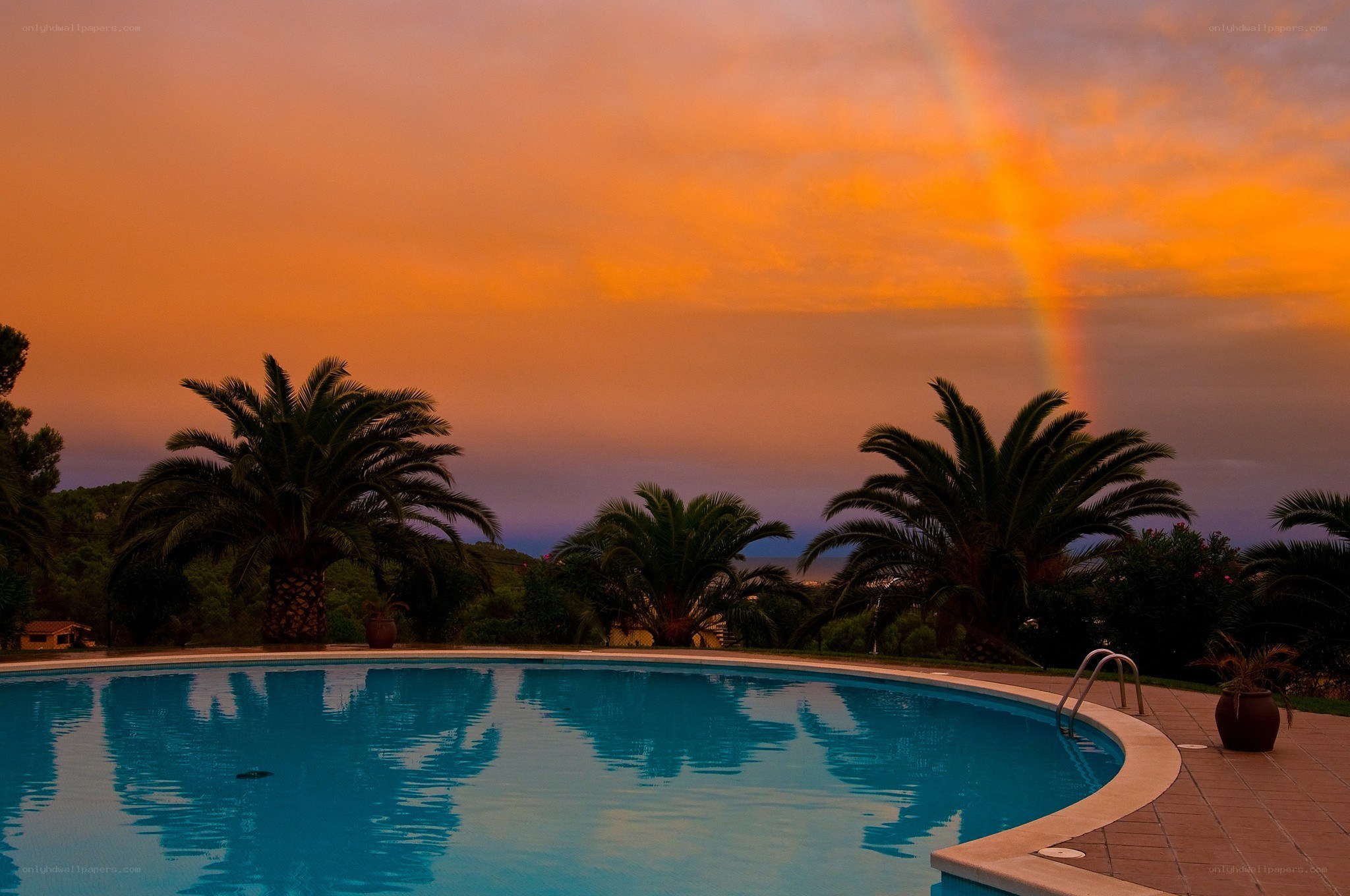 Pool with rainbow at sunset