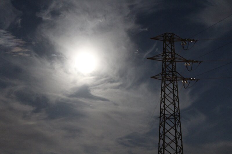 Power line tower under cloudy sky