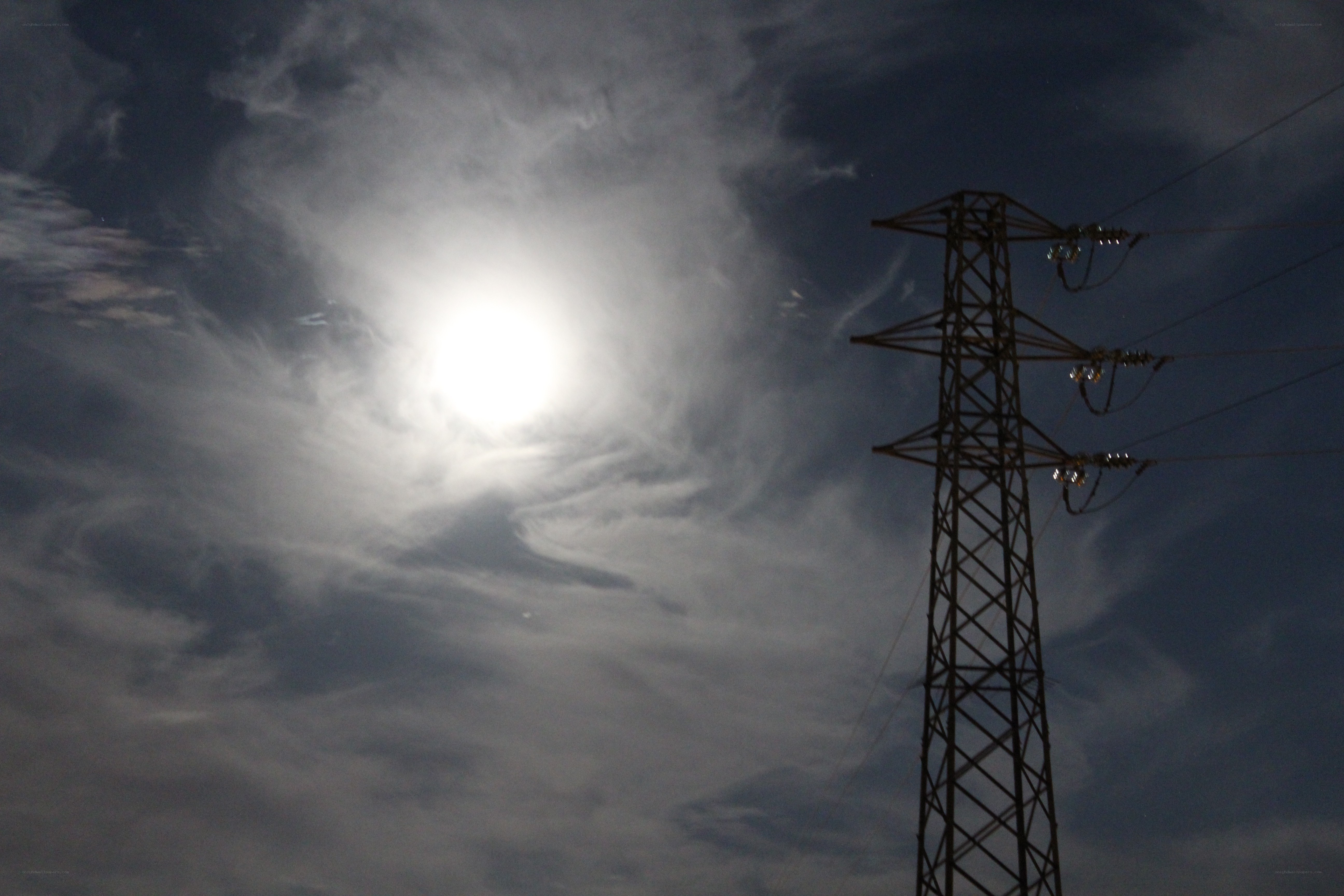 Power line tower under cloudy sky
