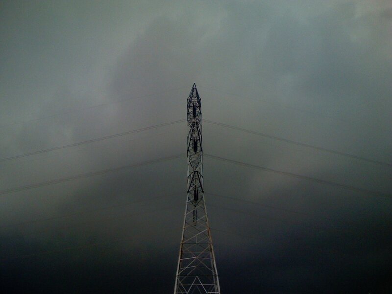 Power line tower under stormy sky