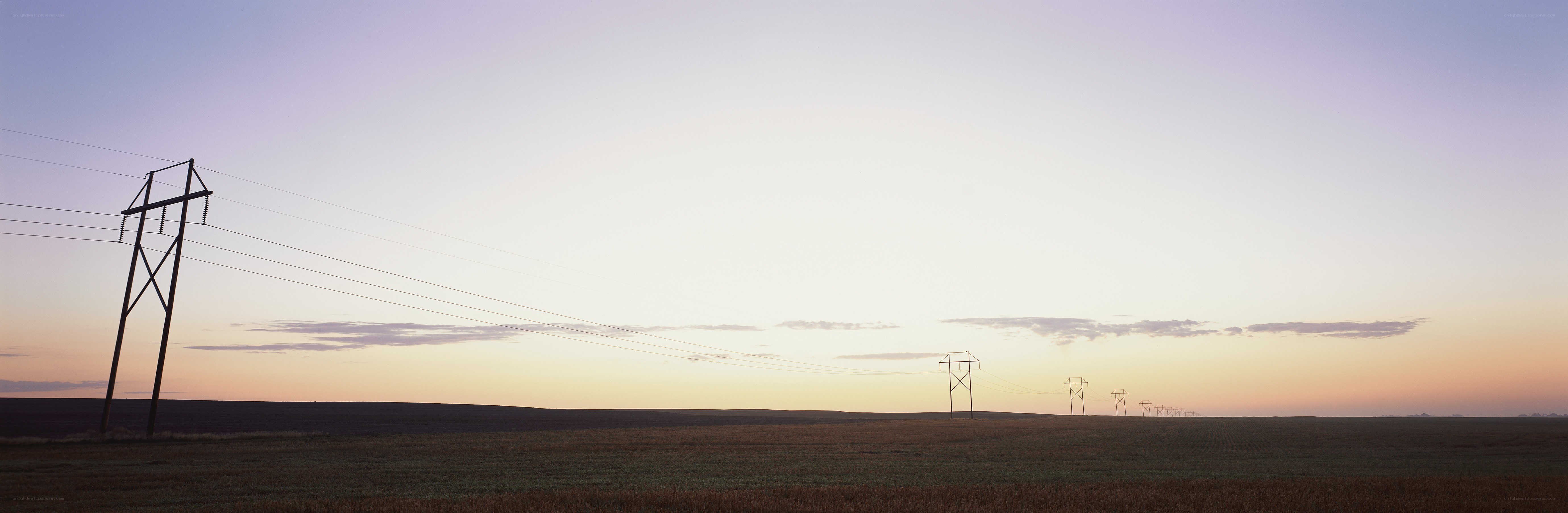 Power lines across a field at sunset
