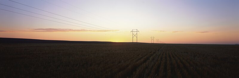 Power lines at sunset over a field
