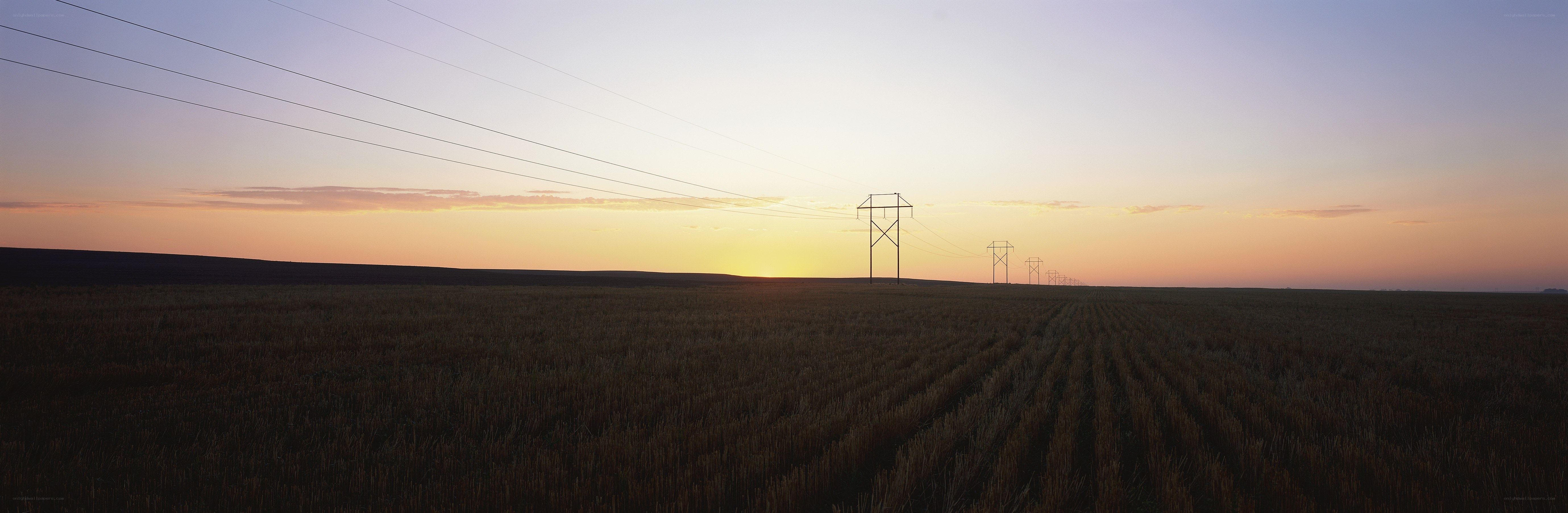 Power lines at sunset over a field