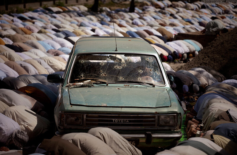 Praying men and a bullet-riddled car