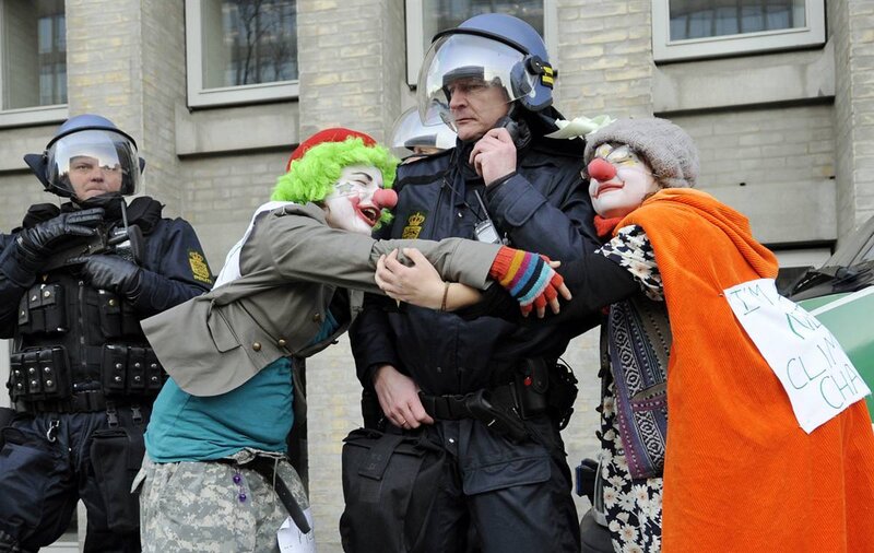 Protesters in clown costumes confront police