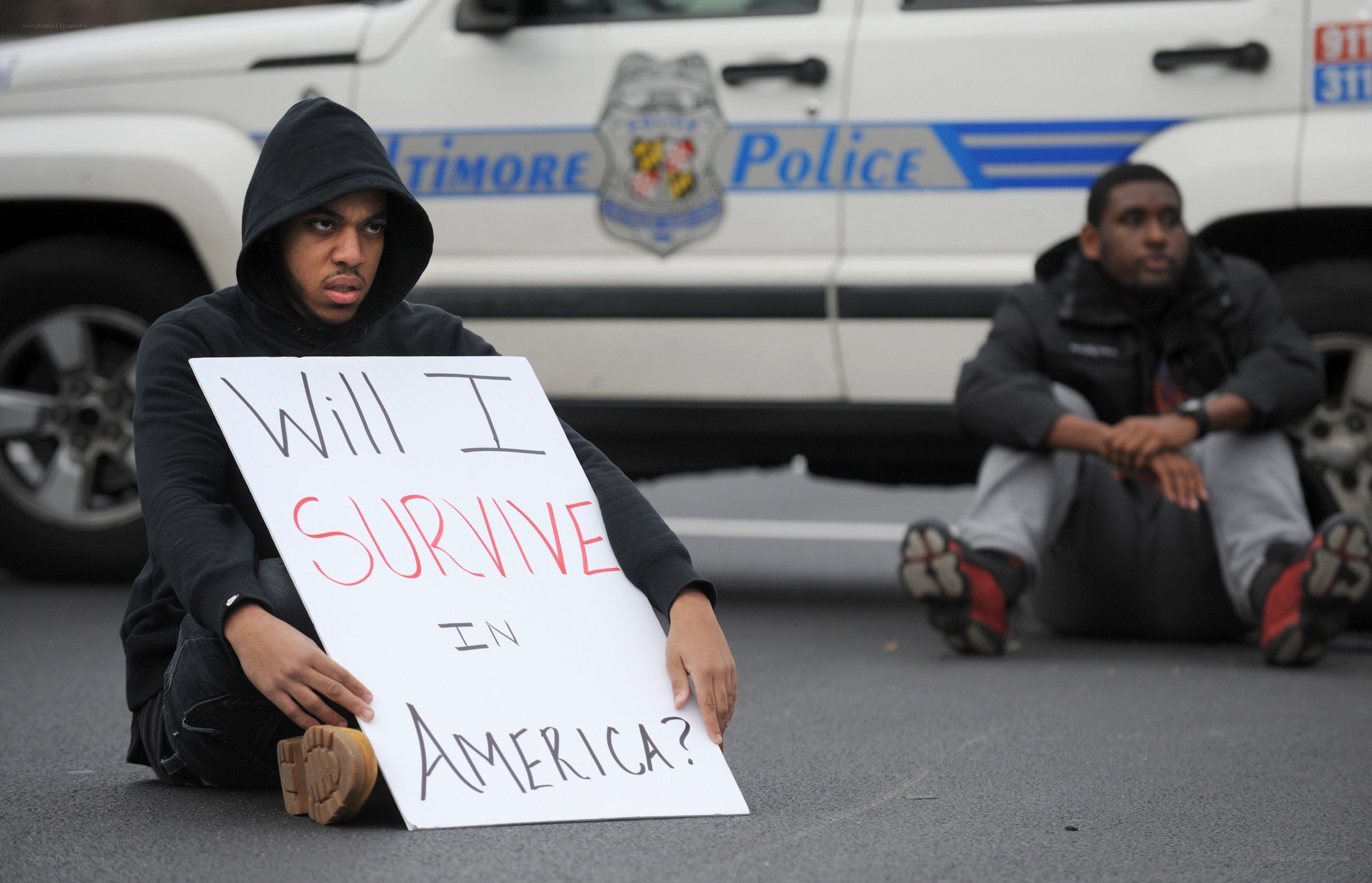 Protesters in front of police car