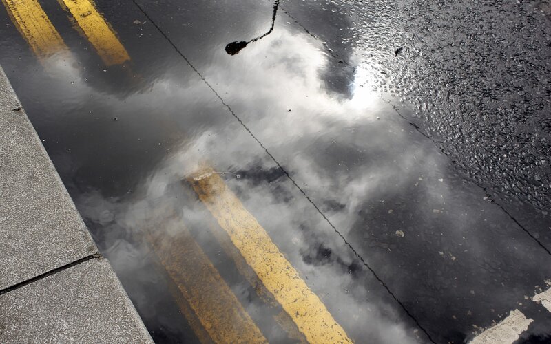Puddle reflecting sky and road lines