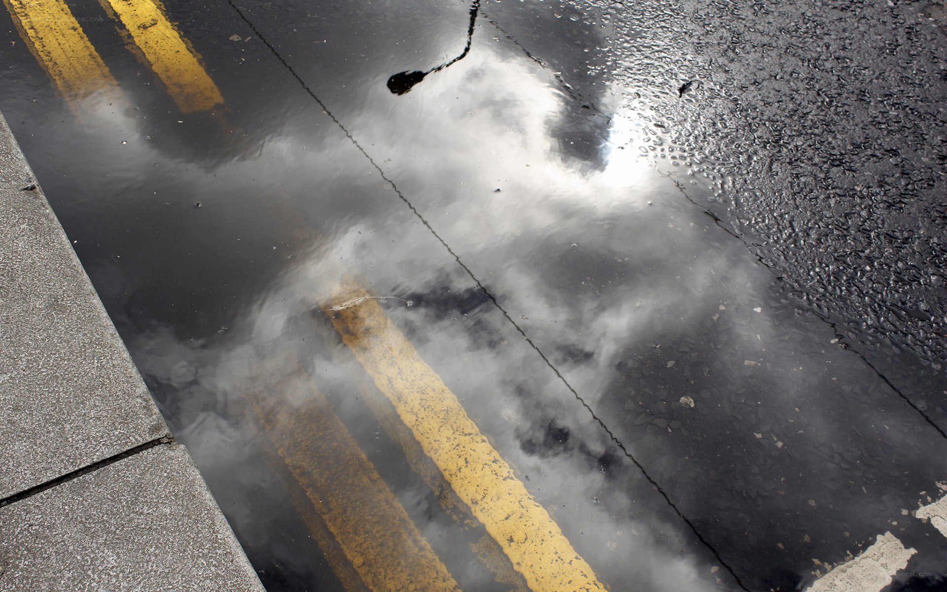 Puddle reflecting sky and road lines