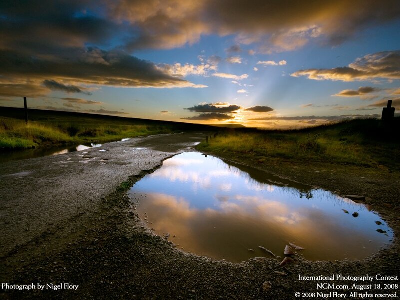 Puddle reflecting sunset sky