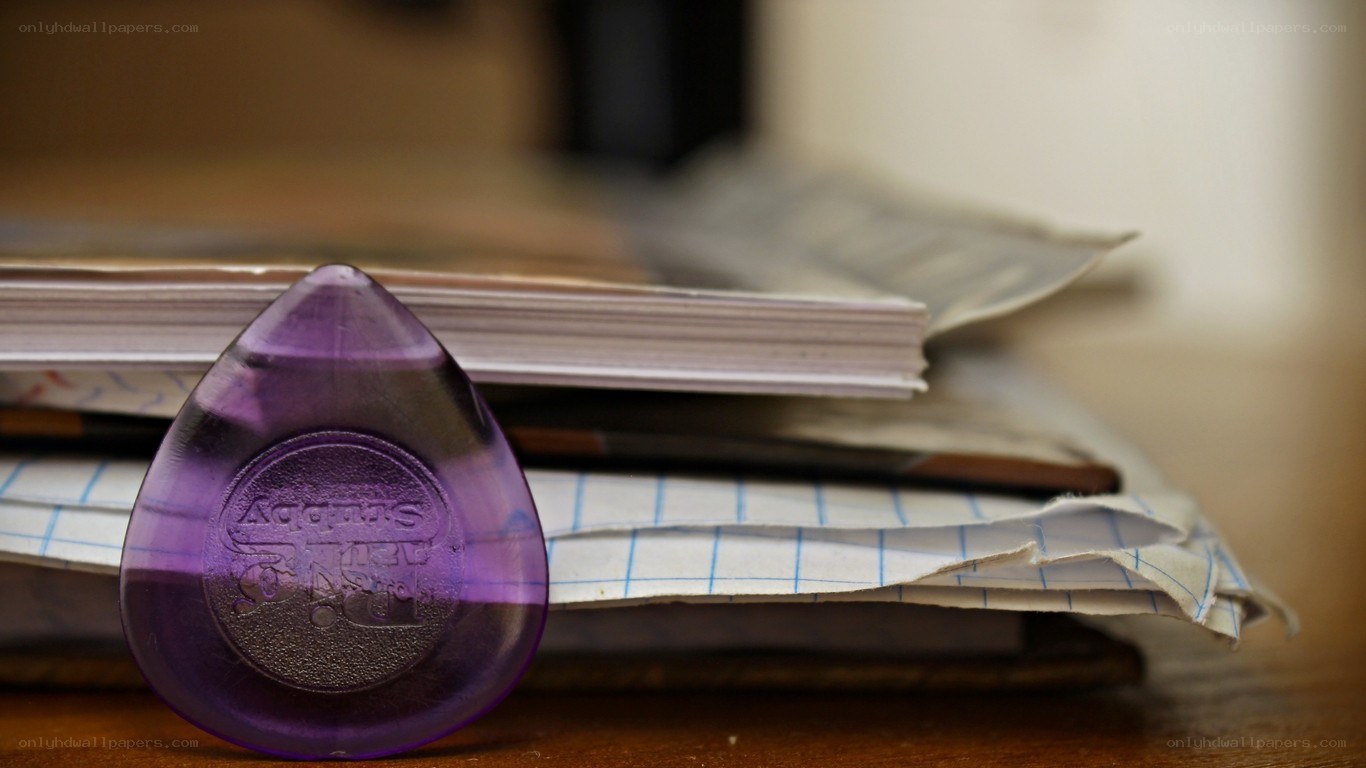 Purple guitar pick on papers