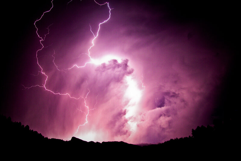 Purple lightning storm over hills