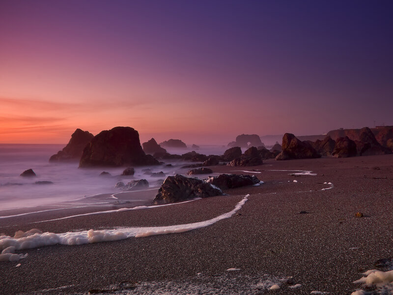 Purple sunset at rocky beach