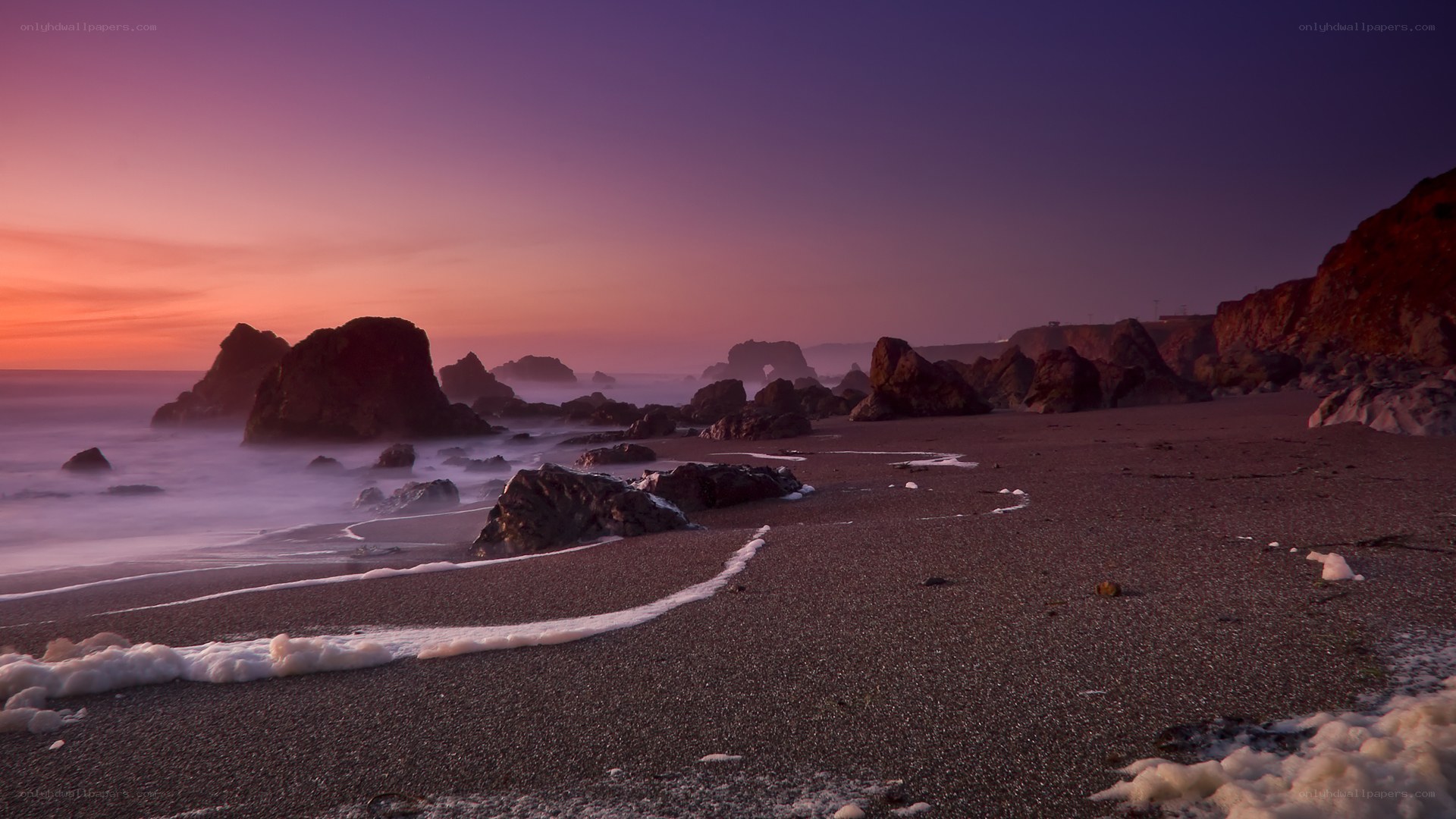 Purple sunset at rocky beach