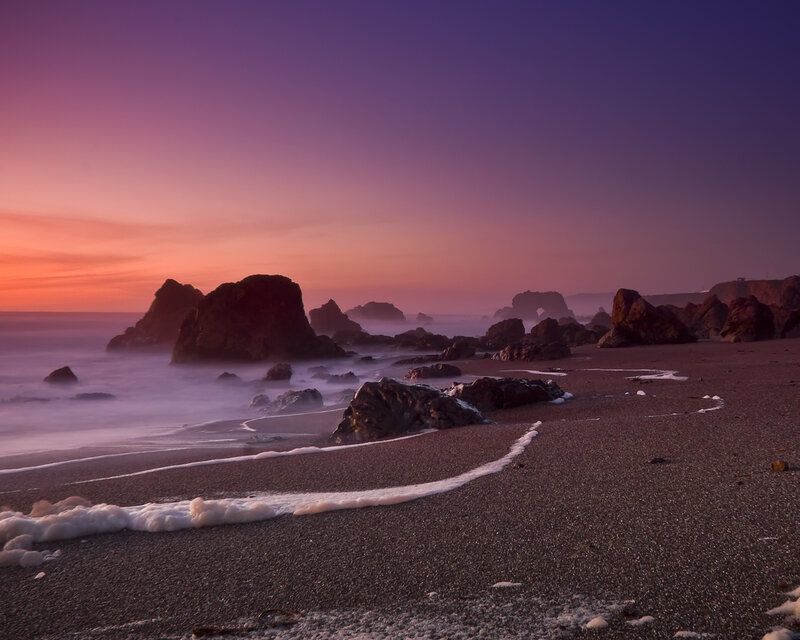 Purple sunset at rocky beach