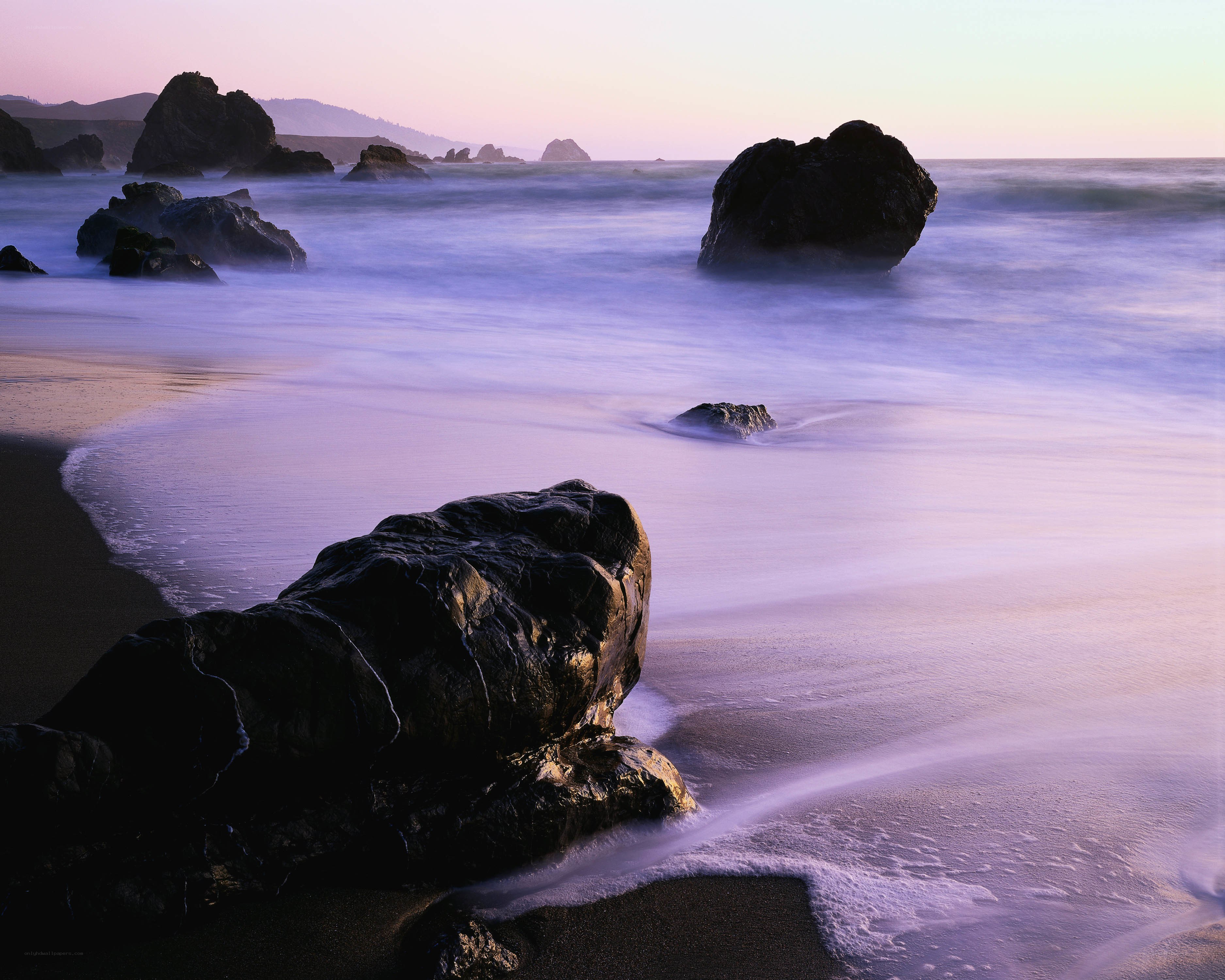 Purple sunset at rocky beach