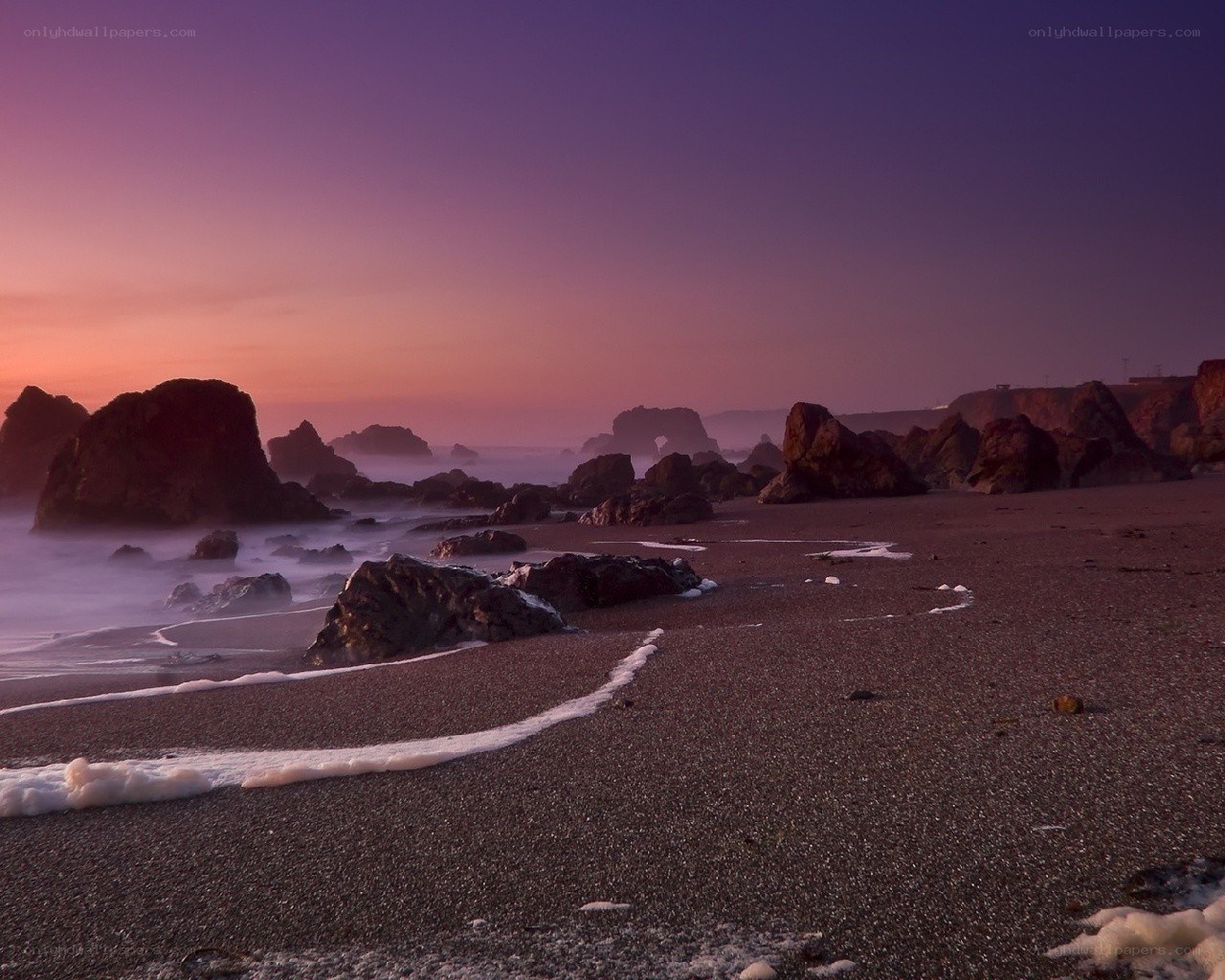 Purple sunset at rocky beach