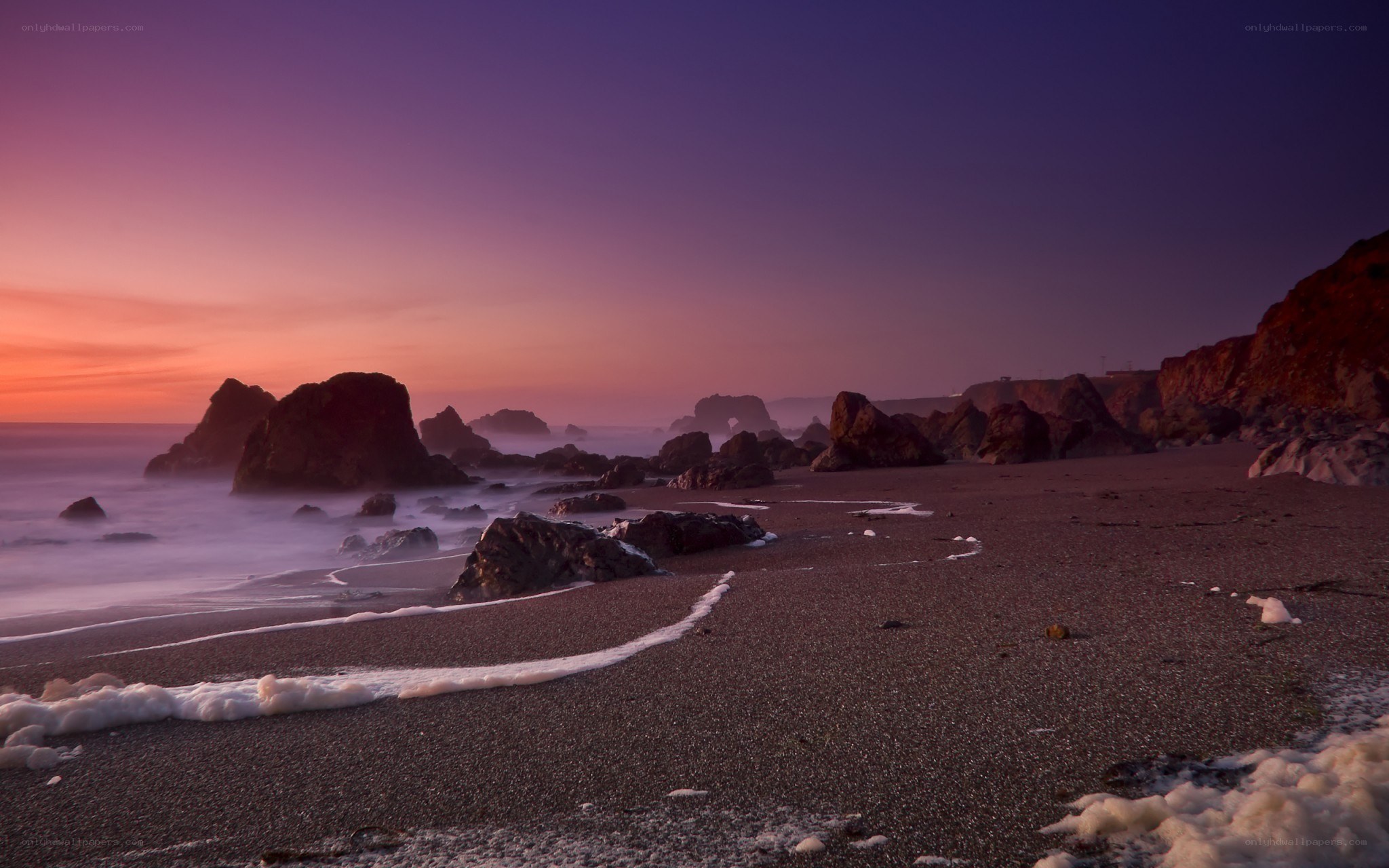 Purple sunset at rocky beach