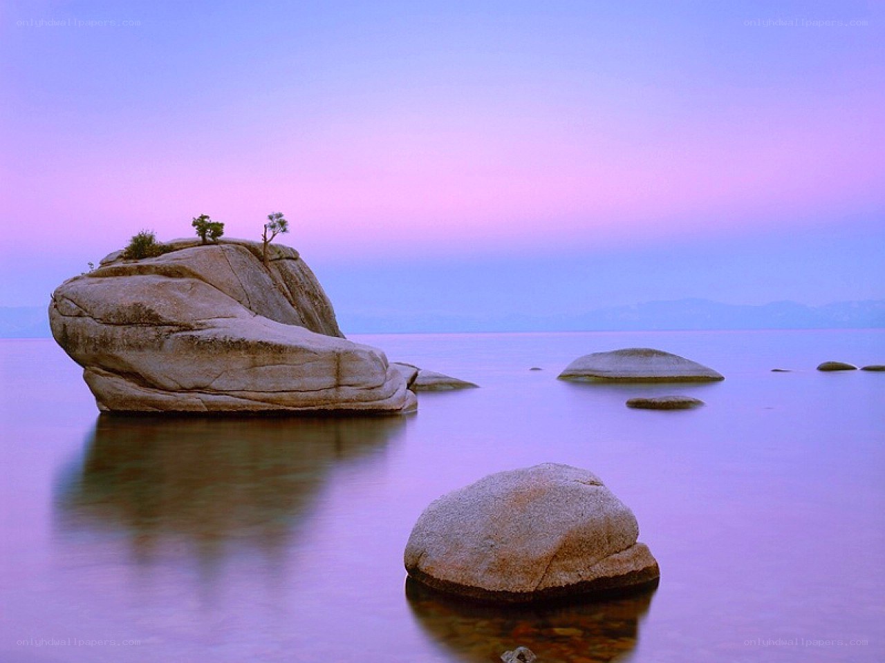 Purple sunset over lake rocks