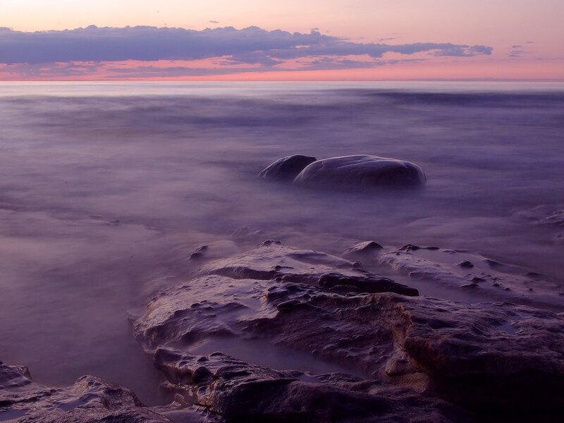 Purple sunset over ocean rocks
