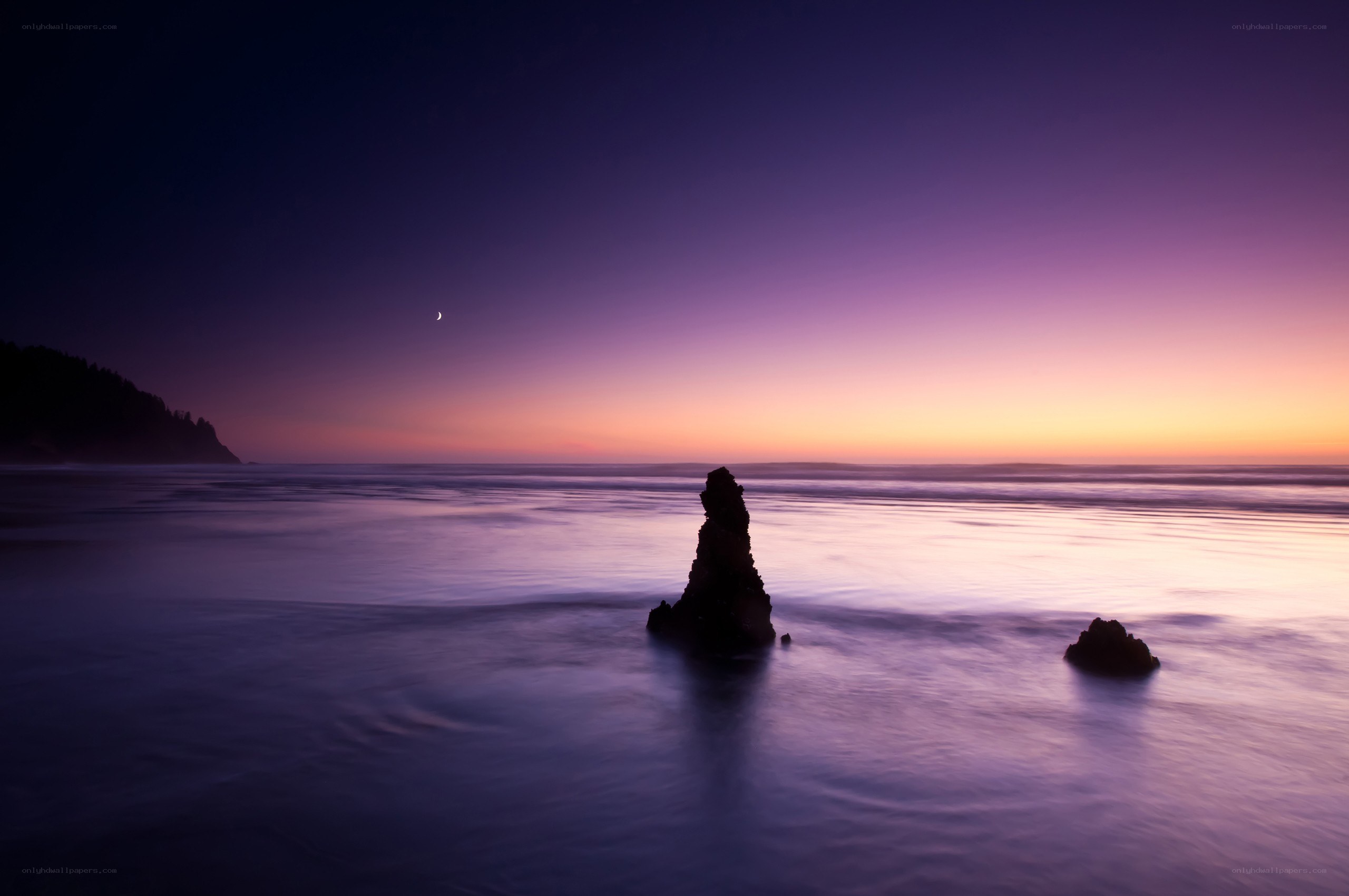 Purple sunset over ocean rocks