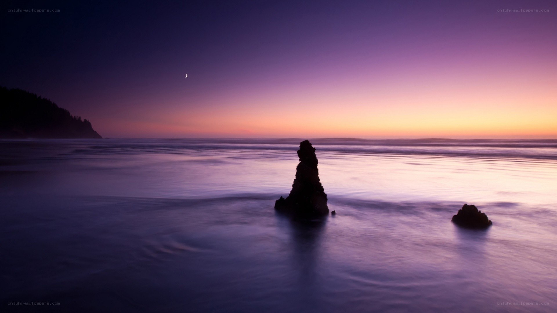 Purple sunset over ocean rocks