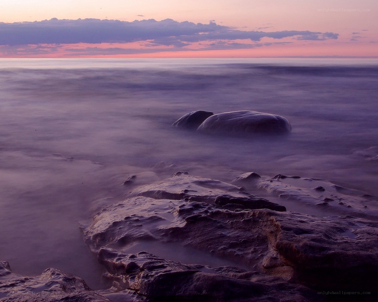 Purple sunset over ocean rocks