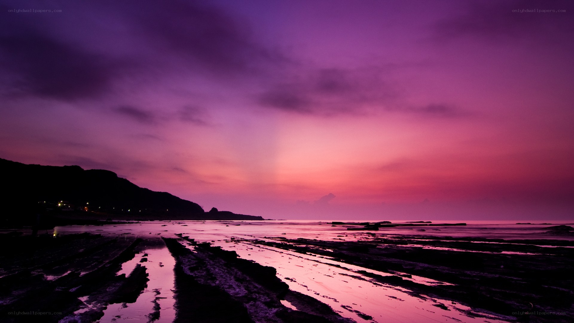 Purple sunset over rocky beach