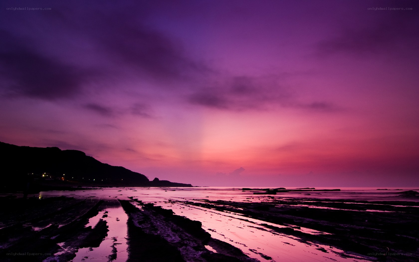 Purple sunset over rocky beach