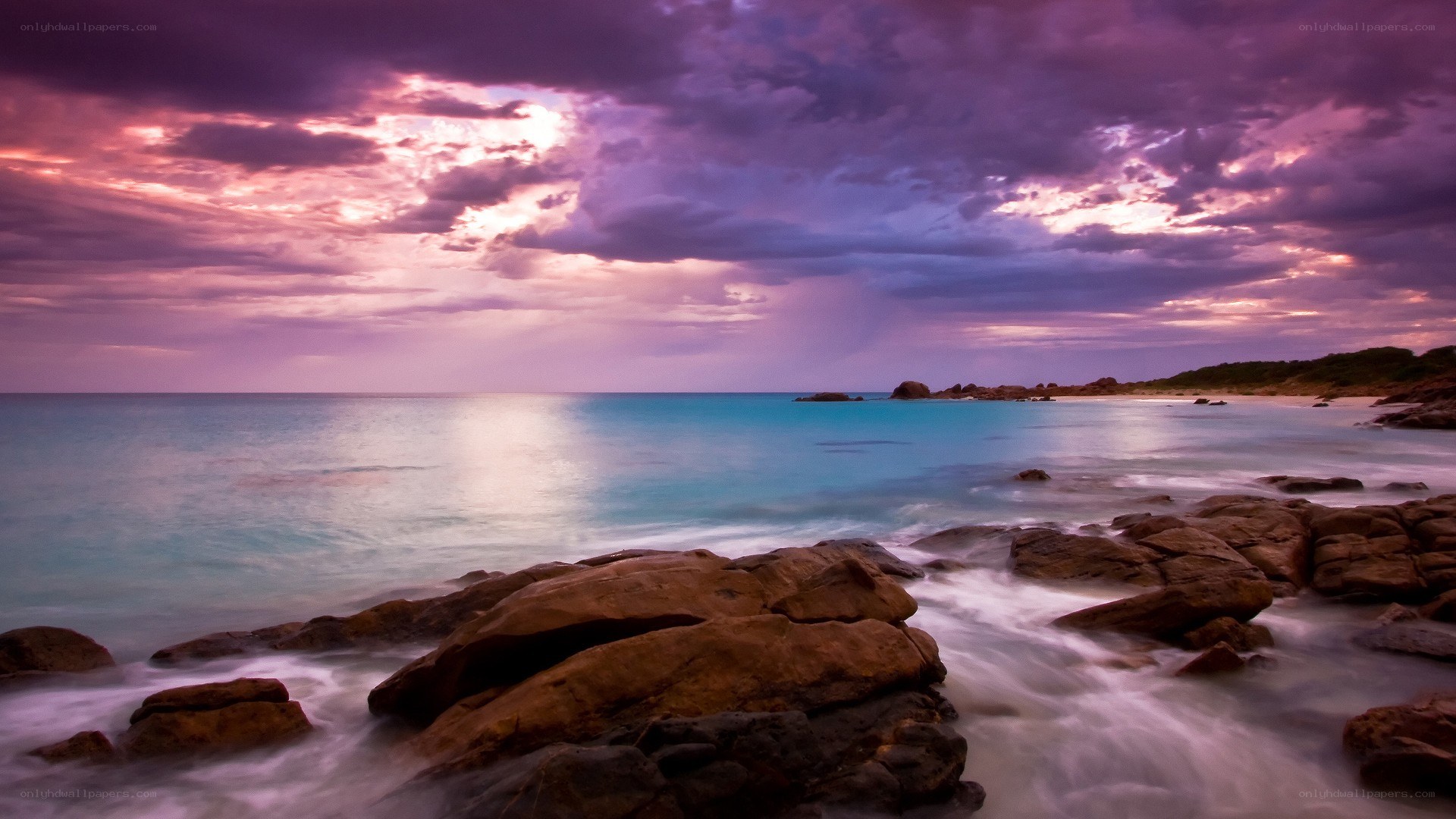 Purple sunset over rocky beach